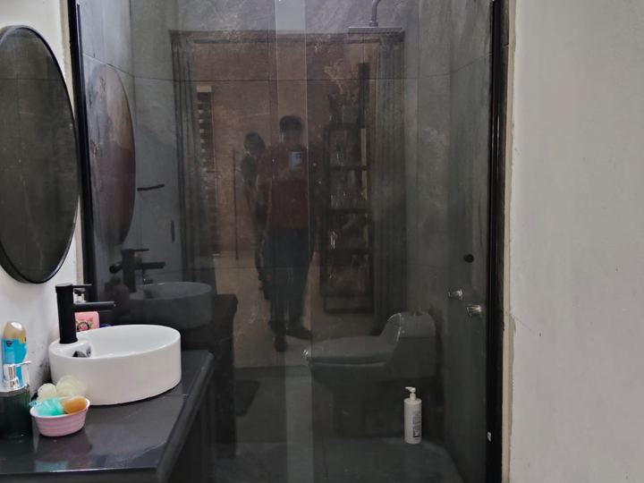 Cancel de baño con perfil negro junto a espejo redondo
