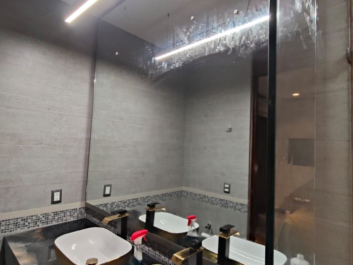 Floor-to-ceiling mirror in a bathroom with gold basins