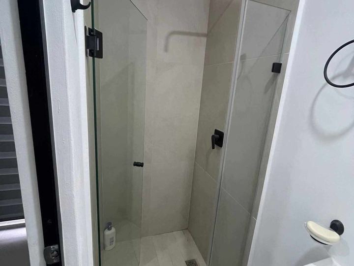 Swing enclosure with black hardware in a compact bathroom