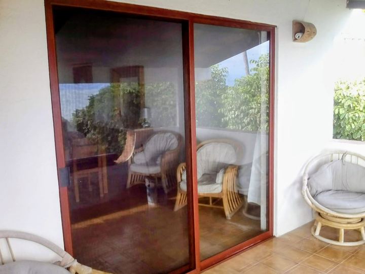 Wood-finish aluminum sliding enclosure with insect screen on a terrace