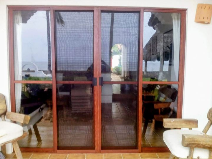 Sliding insect screens on wood-finish glazing facing the sea