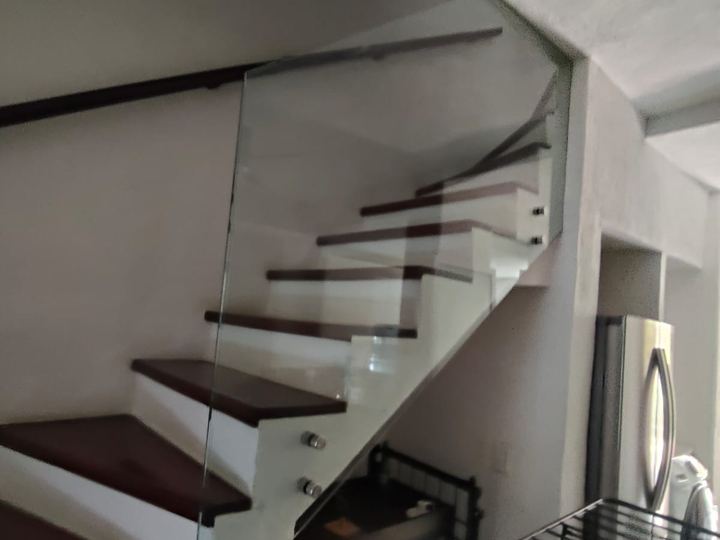 Tempered glass railing on a staircase with a wooden handrail